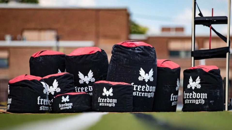 a bunch of different size freedom strength strongman sandbags lined up ready for a competition