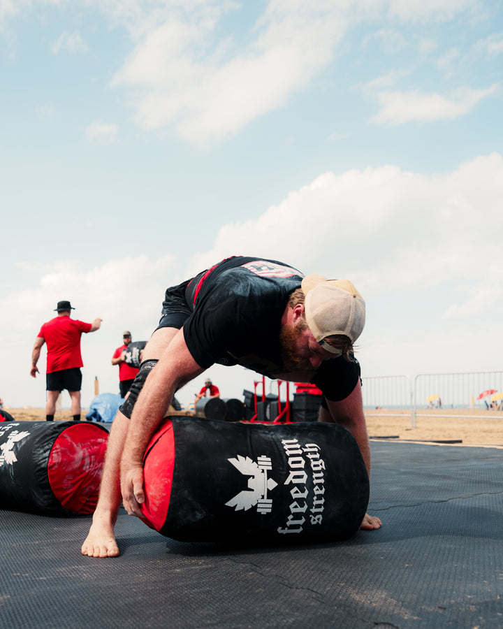 Person using a sand bag with 'Freedom Strength' branding outdoors.